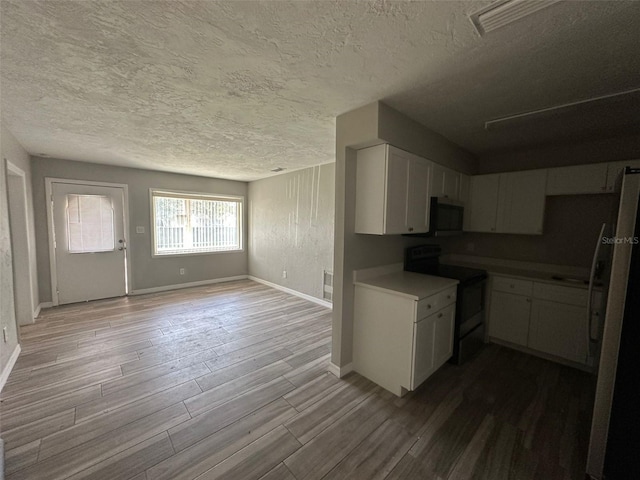 kitchen with black electric range, white cabinets, wood-type flooring, and fridge