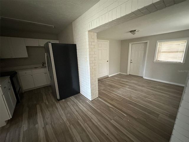 interior space featuring stainless steel refrigerator, dark hardwood / wood-style flooring, white cabinets, and sink