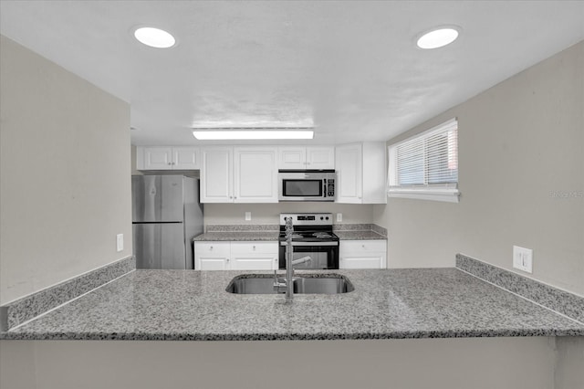 kitchen with light stone countertops, sink, white cabinetry, and stainless steel appliances