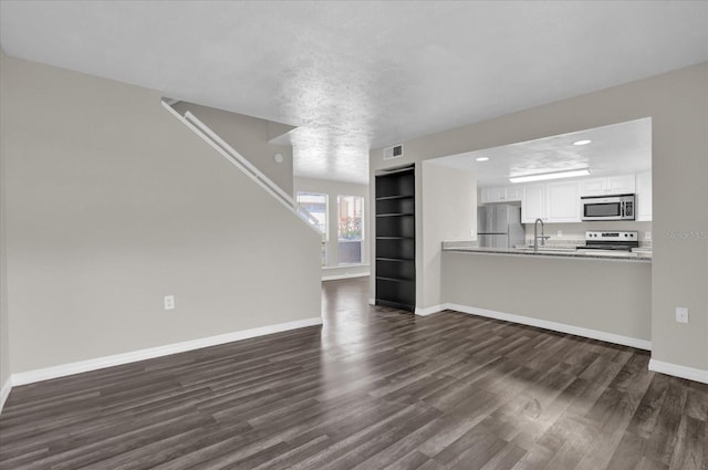 unfurnished living room featuring dark hardwood / wood-style flooring and a textured ceiling