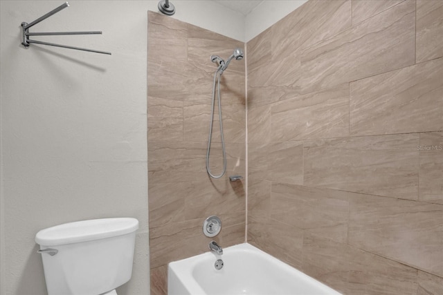 bathroom featuring tiled shower / bath combo and toilet