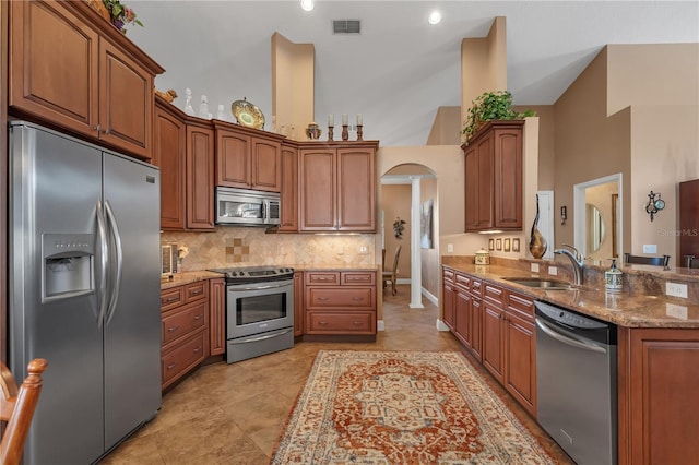 kitchen with light stone countertops, sink, high vaulted ceiling, and stainless steel appliances