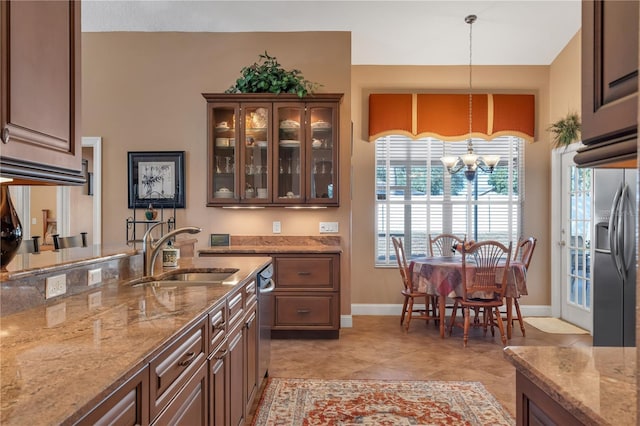 kitchen with sink, hanging light fixtures, light stone countertops, a notable chandelier, and stainless steel appliances