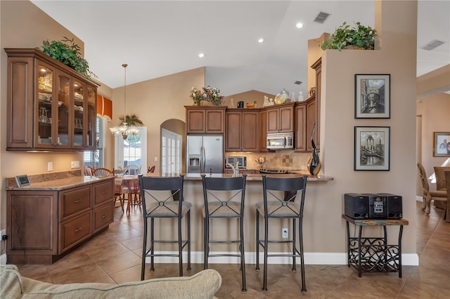 kitchen with hanging light fixtures, stainless steel appliances, a chandelier, lofted ceiling, and light tile patterned flooring