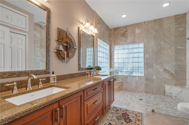 bathroom with vanity, tile patterned floors, toilet, tile walls, and a tile shower