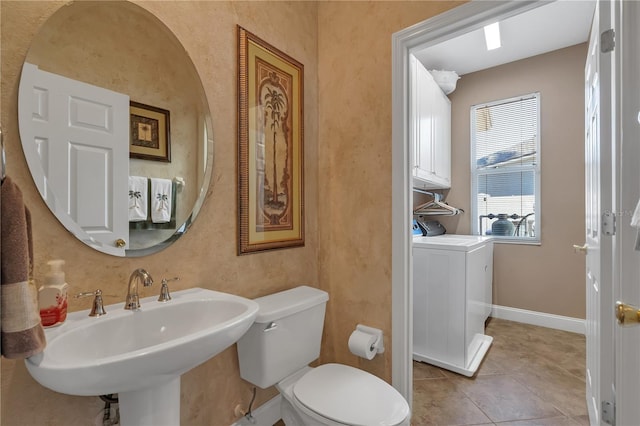 bathroom featuring tile patterned flooring, toilet, washer / dryer, and sink