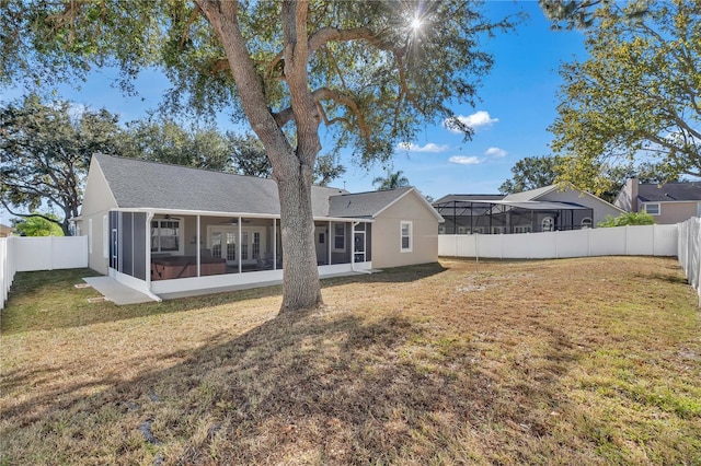 rear view of property with a sunroom and a lawn