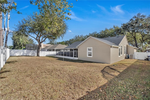 rear view of house with a lawn, central AC, and a sunroom