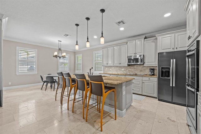 kitchen featuring a kitchen bar, a center island with sink, stainless steel appliances, and a healthy amount of sunlight