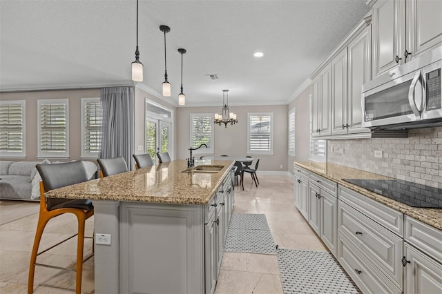 kitchen with a kitchen breakfast bar, ornamental molding, black electric cooktop, a kitchen island with sink, and sink