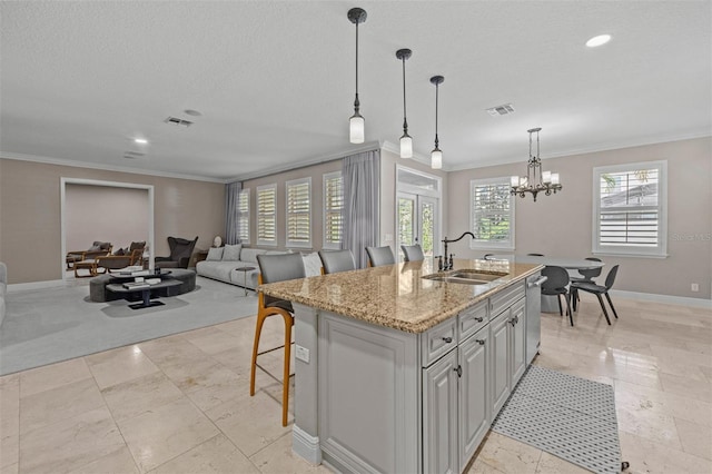 kitchen featuring light stone countertops, sink, an island with sink, and a healthy amount of sunlight