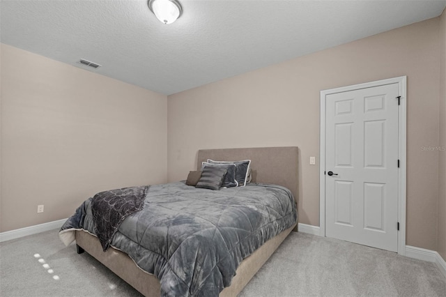 bedroom featuring light carpet and a textured ceiling