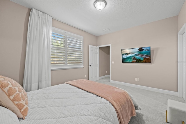 bedroom with a textured ceiling and light colored carpet