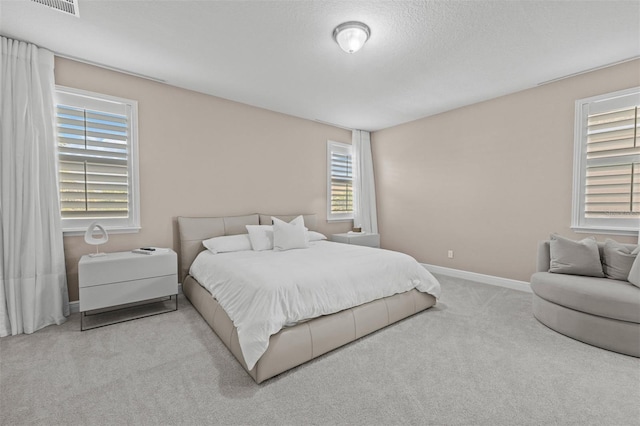 bedroom with light colored carpet and a textured ceiling