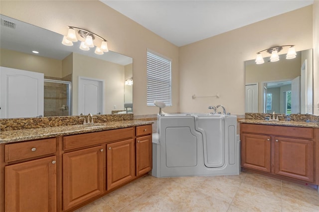 bathroom featuring washer and clothes dryer, plus walk in shower, tile patterned flooring, and vanity