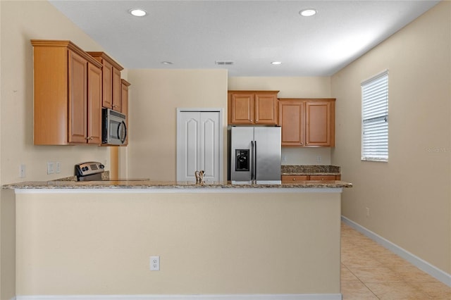 kitchen with light stone countertops, kitchen peninsula, stainless steel appliances, sink, and light tile patterned floors