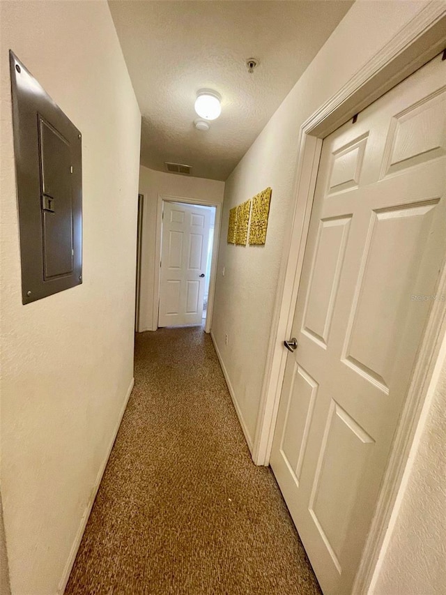 hall with carpet, a textured ceiling, and electric panel