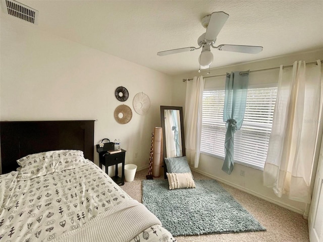 carpeted bedroom featuring ceiling fan and a textured ceiling