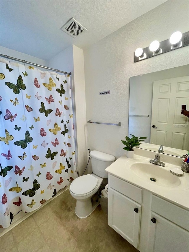 bathroom featuring a shower with shower curtain, vanity, toilet, and a textured ceiling