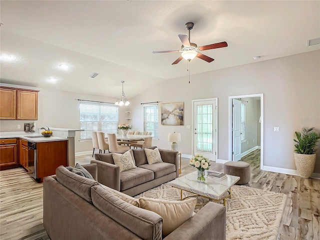 living room with ceiling fan with notable chandelier, light hardwood / wood-style floors, vaulted ceiling, and sink