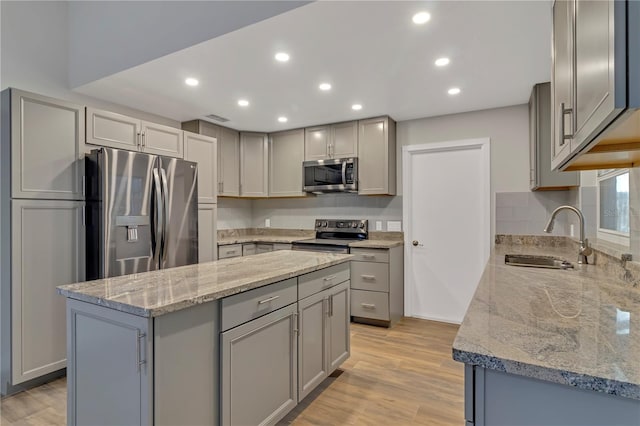 kitchen featuring gray cabinetry, a center island, sink, light wood-type flooring, and appliances with stainless steel finishes