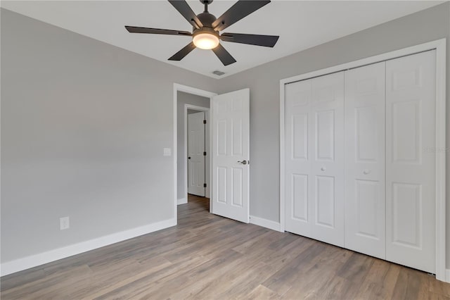 unfurnished bedroom featuring ceiling fan, light wood-type flooring, and a closet