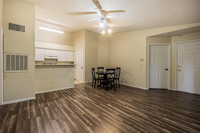 unfurnished dining area with a textured ceiling, ceiling fan, and dark wood-type flooring