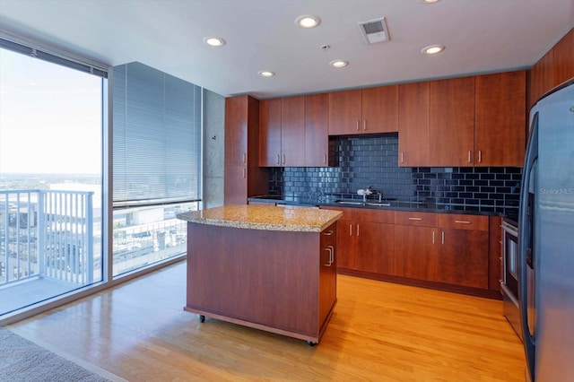 kitchen featuring decorative backsplash, light wood-type flooring, a center island, and sink