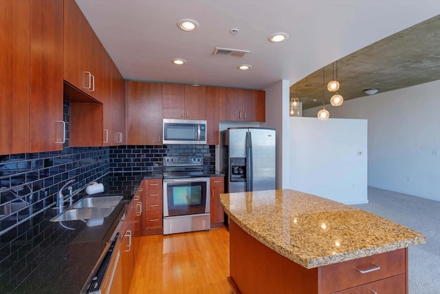 kitchen featuring sink, light hardwood / wood-style flooring, decorative backsplash, a kitchen island, and stainless steel appliances