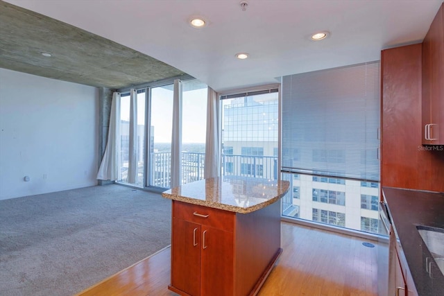 kitchen with a wall of windows, light hardwood / wood-style floors, a kitchen island, and plenty of natural light