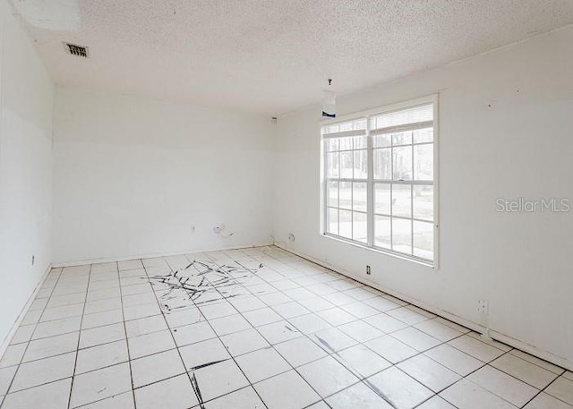 unfurnished room featuring visible vents, a textured ceiling, and light tile patterned flooring