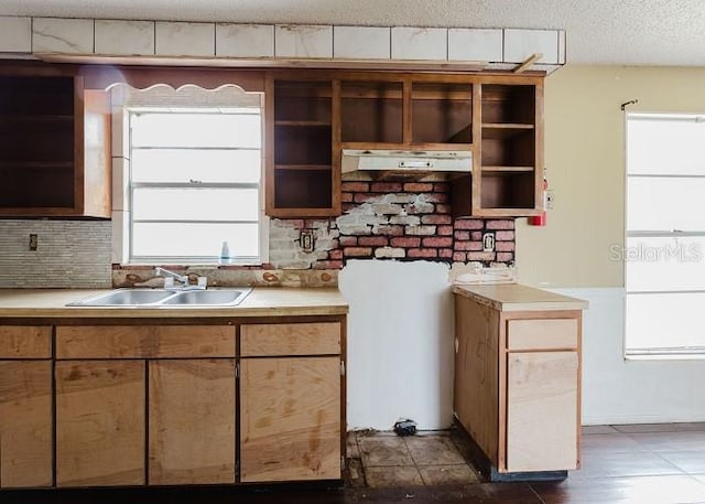 kitchen featuring a textured ceiling, light countertops, tasteful backsplash, and a sink