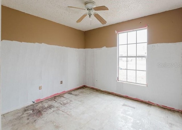 spare room featuring a textured ceiling, light floors, and ceiling fan