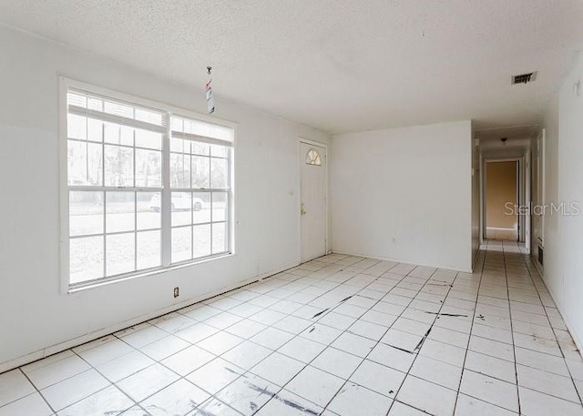 unfurnished room with light tile patterned floors, visible vents, and a textured ceiling