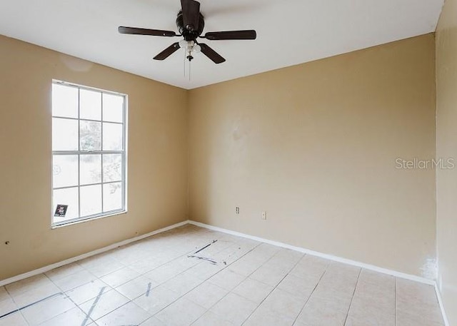 empty room featuring plenty of natural light, a ceiling fan, and baseboards