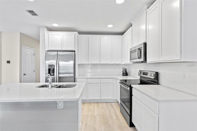 kitchen with white cabinetry, sink, stainless steel appliances, and light hardwood / wood-style floors