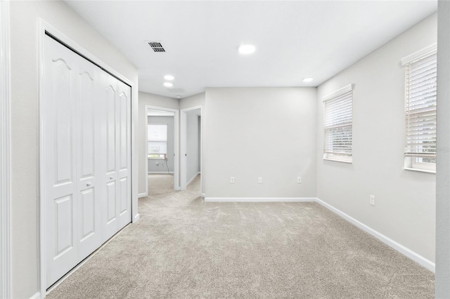 unfurnished bedroom with light colored carpet and a closet