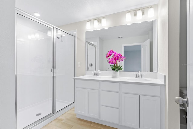 bathroom featuring wood-type flooring, vanity, and a shower with door