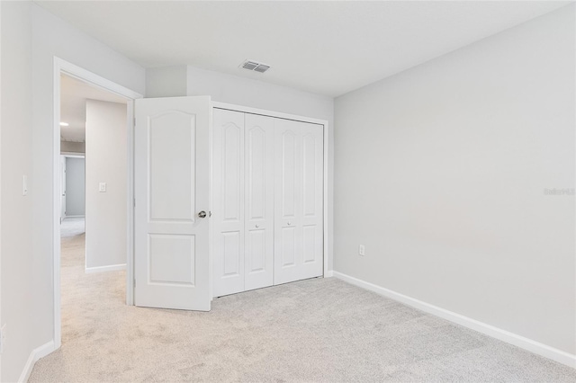 unfurnished bedroom with a closet and light colored carpet