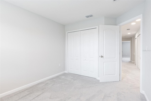 unfurnished bedroom featuring light carpet and a closet