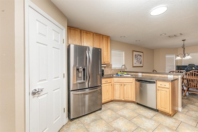 kitchen featuring sink, light brown cabinets, hanging light fixtures, stainless steel appliances, and a notable chandelier