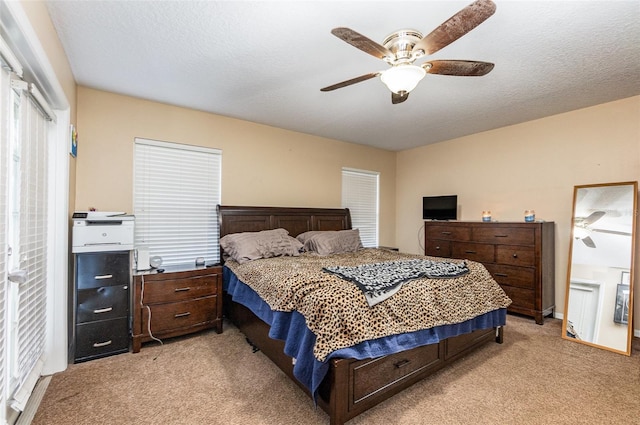 bedroom with ceiling fan, light carpet, and a textured ceiling