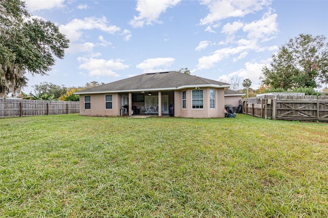 rear view of house featuring a yard and ceiling fan