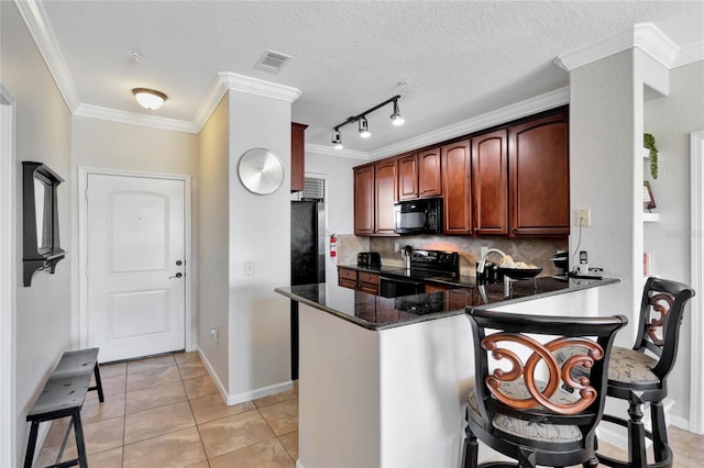 kitchen featuring kitchen peninsula, dark stone counters, decorative backsplash, light tile patterned flooring, and black appliances