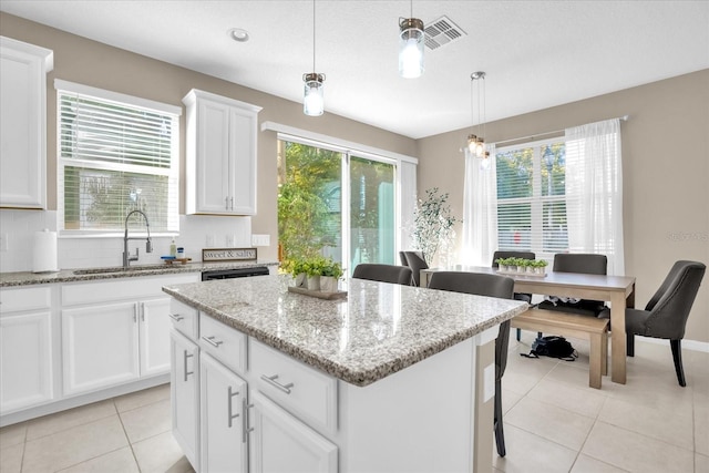 kitchen featuring decorative backsplash, pendant lighting, a kitchen island, and sink