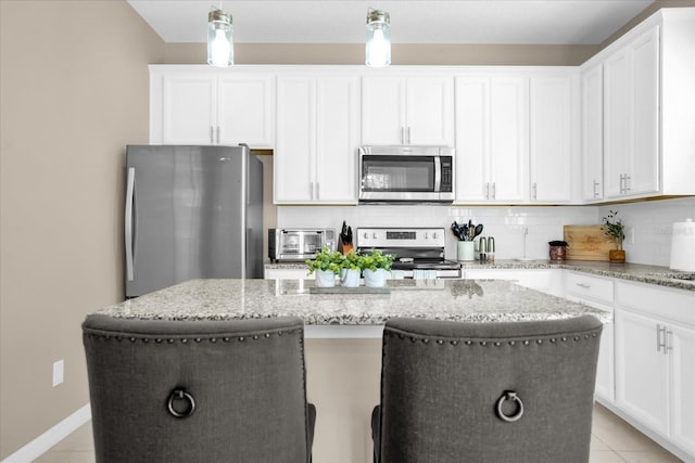 kitchen featuring white cabinetry, light stone counters, a kitchen island, and appliances with stainless steel finishes