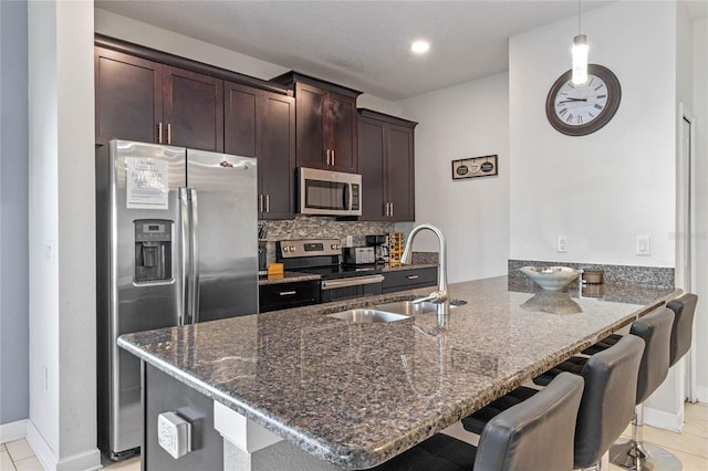 kitchen featuring sink, hanging light fixtures, stainless steel appliances, kitchen peninsula, and dark stone counters