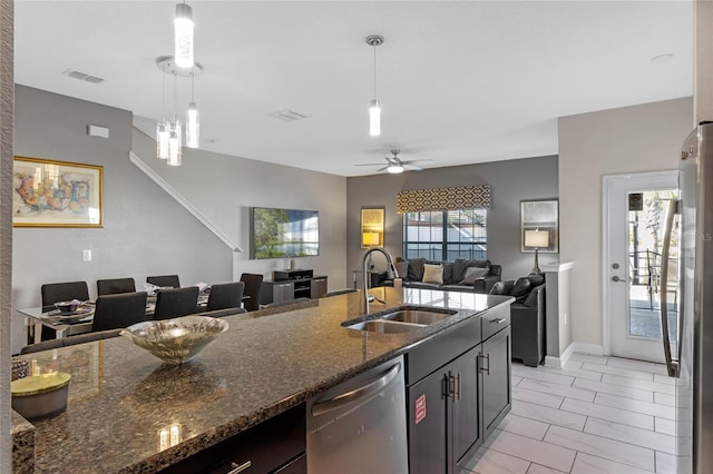 kitchen featuring decorative light fixtures, stainless steel appliances, dark stone counters, and sink