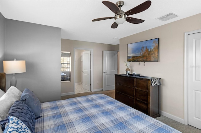 bedroom with ceiling fan, ensuite bathroom, and light carpet