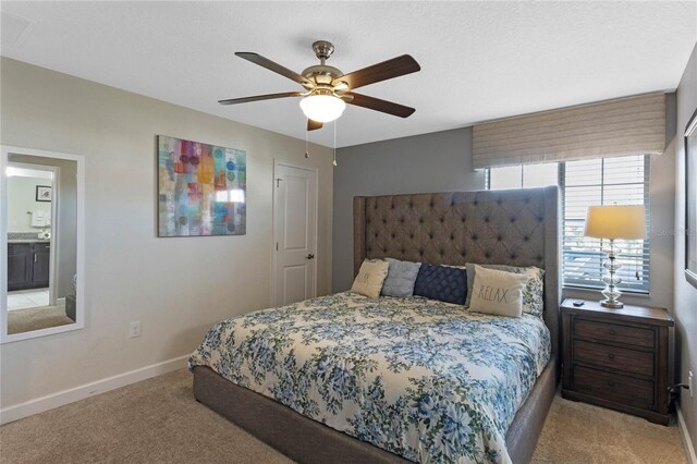 bedroom featuring connected bathroom, ceiling fan, and light carpet